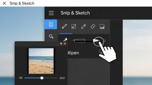 Eine Nahaufnahme der „Snip & Sketch“-App-Oberfläche im Dark Mode. Ein pixeliger Handcursor zeigt auf ein Stiftwerkzeug-Symbol. Ein kleines Vorschaufenster in der Ecke zeigt eine Strandszene mit einem Zoom-Regler.
